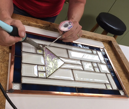 Student soldering stained glass project. 