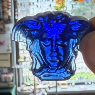 Deep blue glass bust featuring a human face, held up in front of a window display.