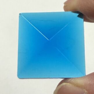 Blue square envelope being held by a finger at the top-right and bottom-right corners. The flap is closed, creating a triangular shape in the center.