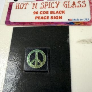 Close-up of a black surface with a small square button displaying a green peace sign