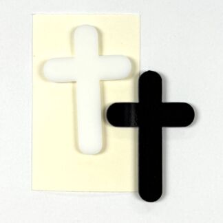 White cross cutout on a pale card beside a solid black cross, showing contrast between light and dark.