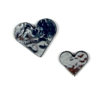 Two metallic heart-shaped charms, one large dark blue and one small silver with brown patches nearby on a white background.