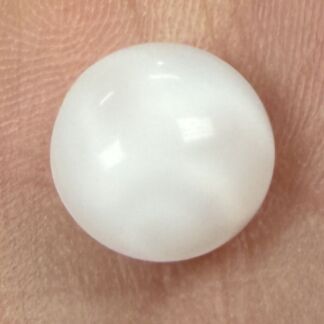 Close-up of a smooth white spherical object resting on a fingertip.