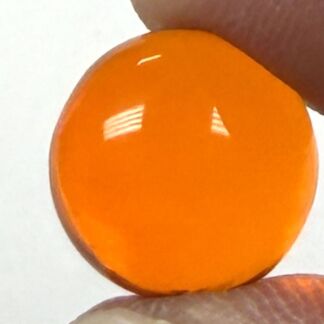 Close-up of an orange, glossy round bead held between fingers.