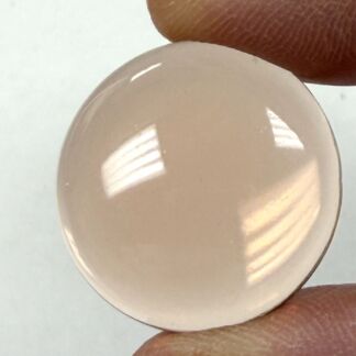 Close-up of a clear contact lens held between two fingers, showing a smooth curved surface and reflections.
