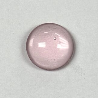 Round pink pill resting on a light gray surface, glossy with reflections on its edges